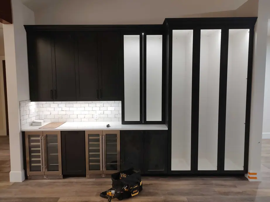 Dark bar cabinetry with lit glass doors and under-cabinet light, finish wiring by Wattsmart Electric