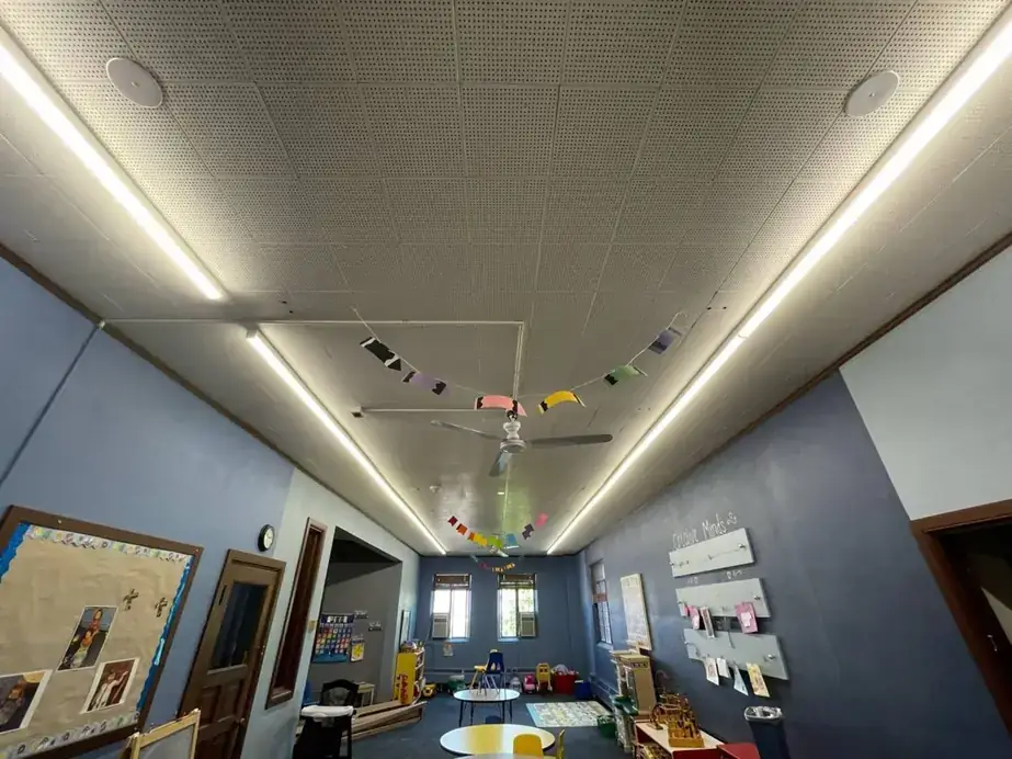 Long LED strip fixtures running down the ceiling of a classroom