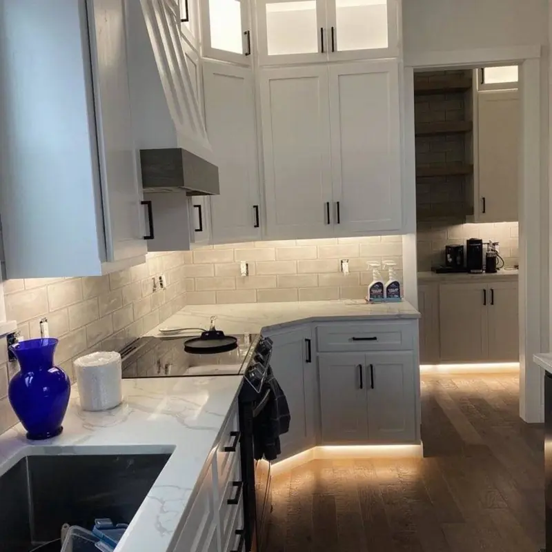 A white kitchen with under-cabinet and toe-kick LED lighting switched on