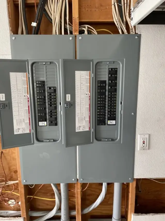 Two new breaker panels side by side in an open wall, wired by Wattsmart Electric