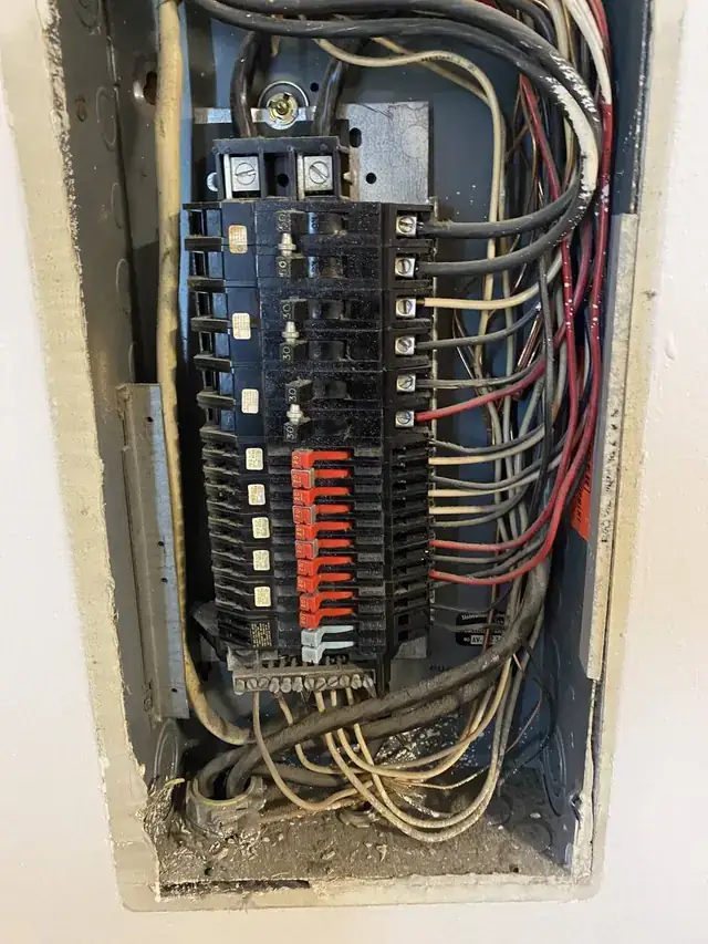 The inside of an older breaker panel crowded with wiring, the kind of panel an electrical inspection looks at closely