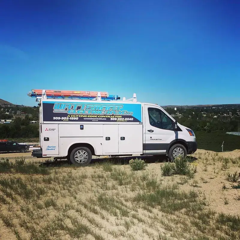 A Wattsmart Electric service van parked on a dry sage hillside under a deep blue sky
